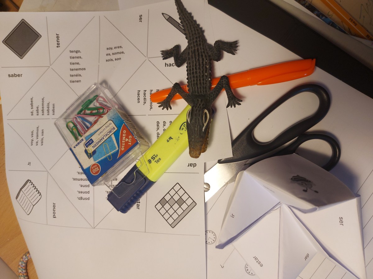 EIn Foto von etwas Bastelmaterial, eine Druckvorlage für ein Spiel und ein Gummikrokodil